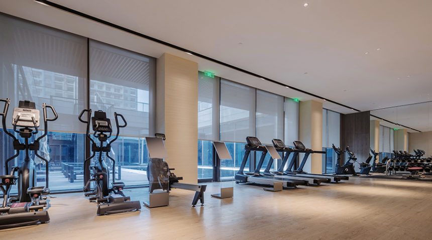 Interior of gym with treadmills and elliptical machines lined up in a row