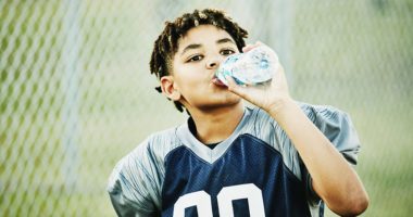 Young football player drinking from water bottle after football game