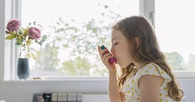 Young girl using pink asthma inhaler