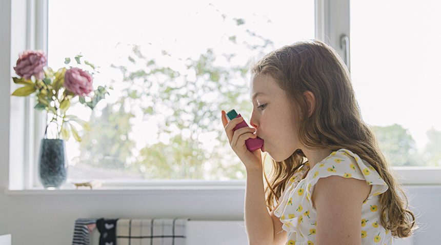 Young girl using pink asthma inhaler