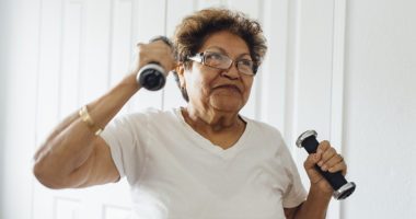 Midshot of older woman lifting light dumbbells at home