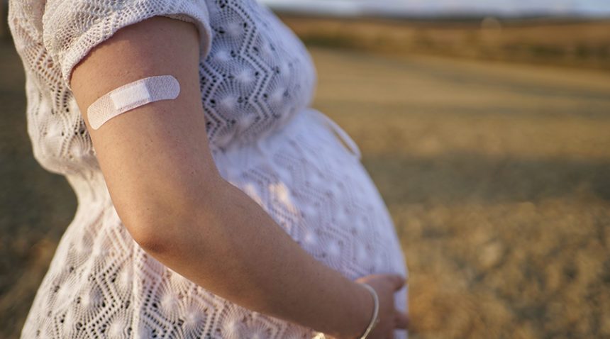 Lateral view of arm of a pregnant woman with a adhesive bandage after the vaccine.