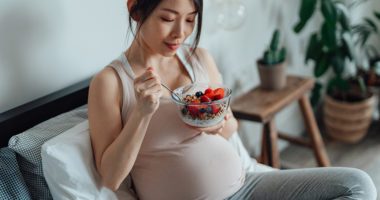 Pregnant woman eating bowl of berries
