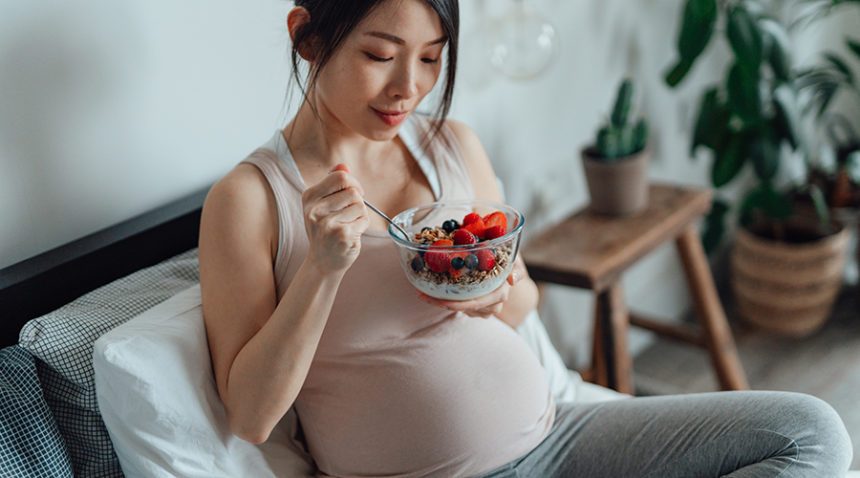 Pregnant woman eating bowl of berries