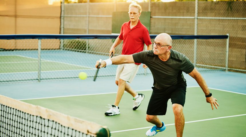 two older men play doubles pickleball