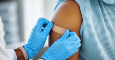 close-up image of provider putting band-aid on a patient's arm