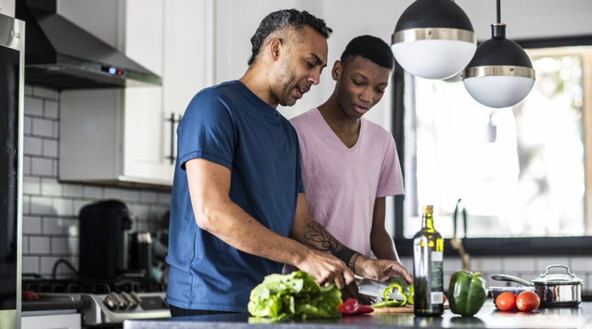 Older man and younger man prepare vegetables together in a sleek home kitchen
