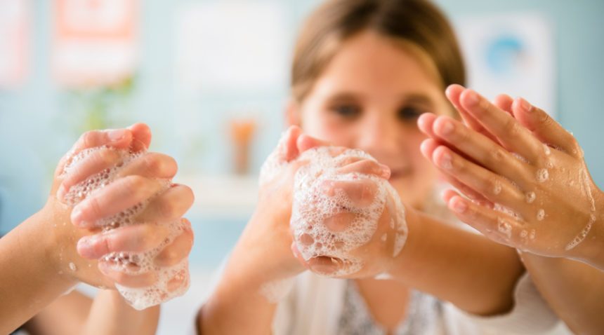 close-up image of three children washing their hands with sudsy soap