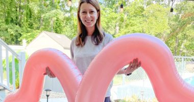UNC Health lung cancer patient Emily in her front yard, holding two pink heart-shaped balloons