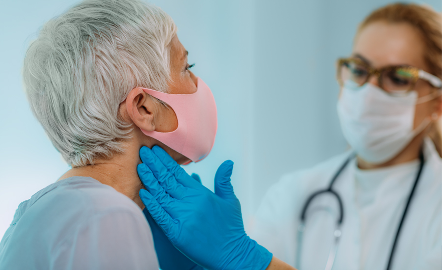 doctor wearing face mask and hand gloves feels the sides of a female patient's neck