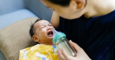 newborn baby cries while mother tries to offer a bottle