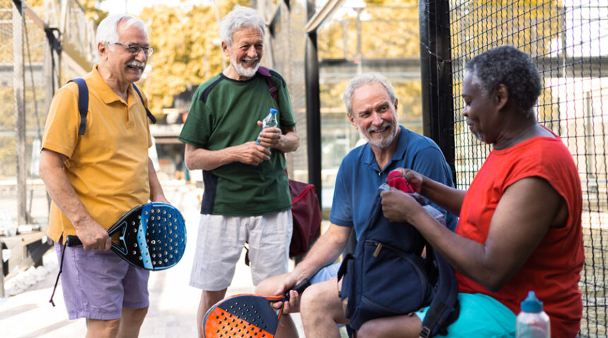 group of men chat outside of a tennis court