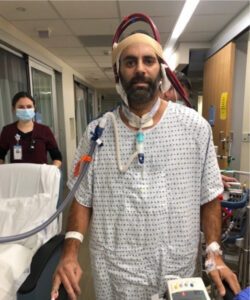 Sean walks through the hospital halls hooked up to the ECMO machine, UNC nurse walking behind him
