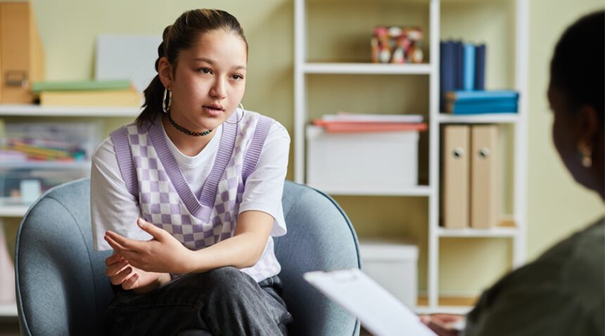 middle-school aged girl sits on couch, talking to adult who is out of frame