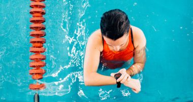 overhead shot of an athletic woman checking her smart watch in the swim lane of a pool