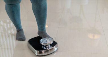 close-up shot of woman wearing exercise leggings, about to step onto a bathroom scale