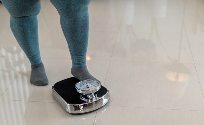 close-up shot of woman wearing exercise leggings, about to step onto a bathroom scale