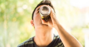 teenage boy takes a big drink from a can