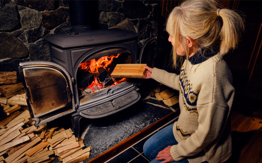 Woman loads wood into a wood-burning fireplace indoors