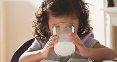 toddler girl drinks a glass of milk