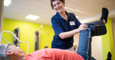 Physical therapist helps a patient bend their leg back to improve hip mobility