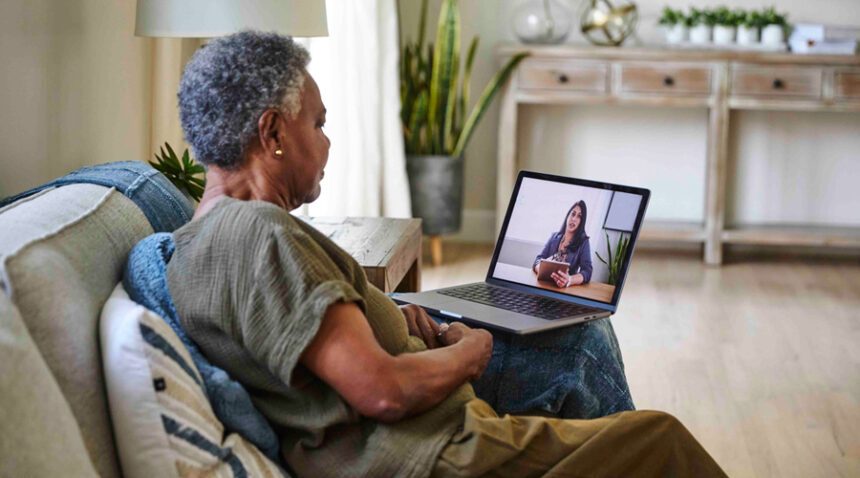 senior woman video chats with a provider on a lap top, sitting in a living room