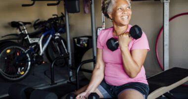 Smiling woman with gray hair lifts weights in a gym