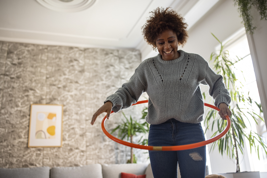 Smiling woman plays with a hula hoop in her living room