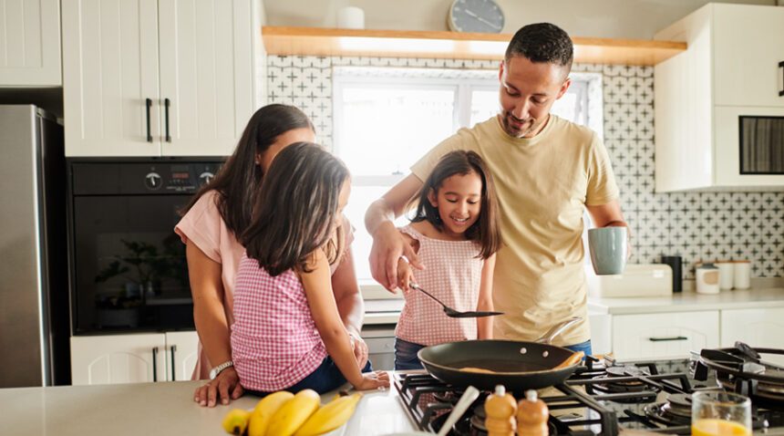 Family of mom, dad, and two girls make breakfast in their kitchen