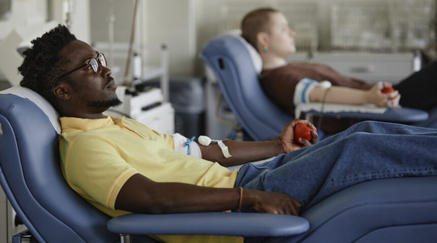 young man sits in medical chair, donating blood