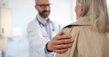 Blurred image of a medical provider placing an assuring hand on a patient's shoulder