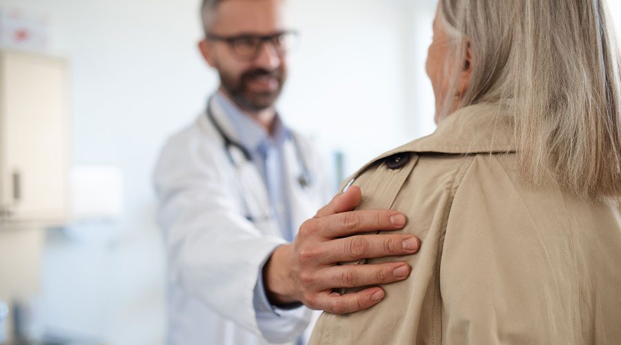 Blurred image of a medical provider placing an assuring hand on a patient's shoulder