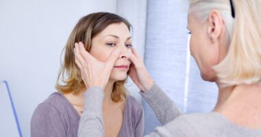 A provider places her hands on the sinus pressure points of a patient's face