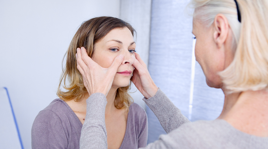 A provider places her hands on the sinus pressure points of a patient's face