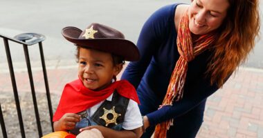 Little boy dressed up as cowboy with his mom standing behind him