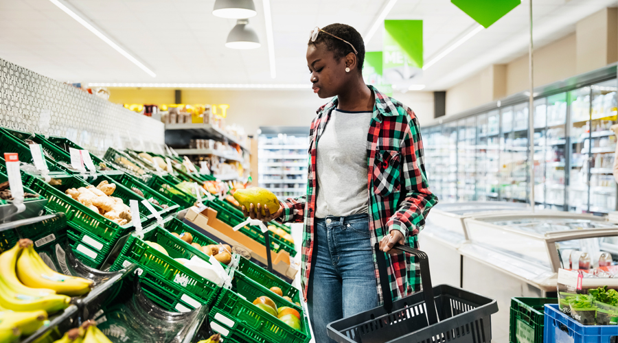 young 20-something woman shops in the produce aisle of the grocery store