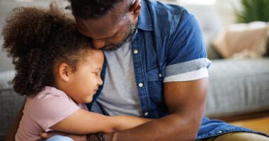 Father and young daughter hug