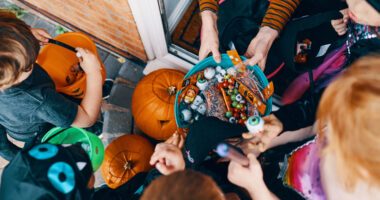 top-down image of a group of kids in costumes reaching into a bowl for some candy