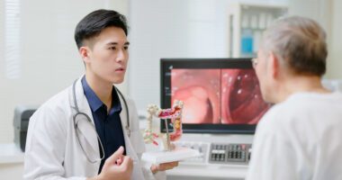 Digestive Health provider holds a model of the intestines while speaking to a patient