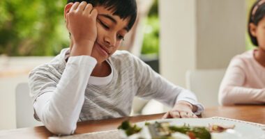 a child looks at his dinner plate reluctantly