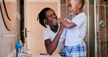 mom and son laugh while the son brushes his teeth