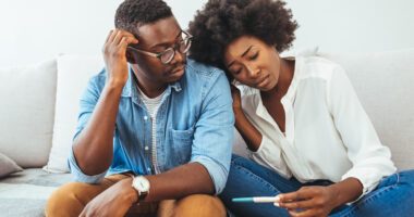 couple looks sadly at a pregnancy test stick