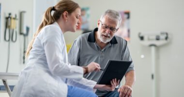 Medical provider points to, speaks about a medical chart with a patient