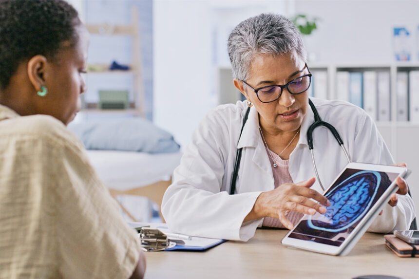 A doctor shows a patient a brain scan image on a tablet while explaining the results during a medical consultation