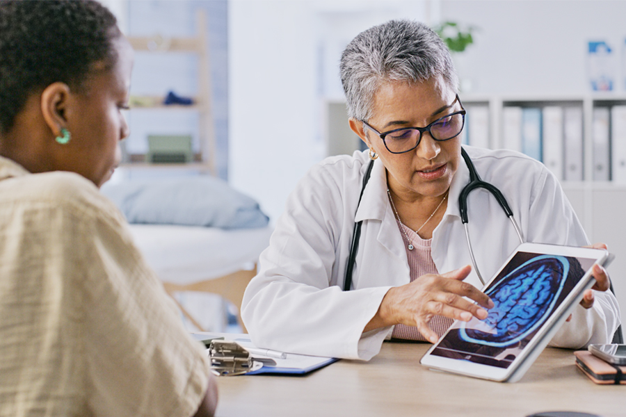 A doctor shows a patient a brain scan image on a tablet while explaining the results during a medical consultation