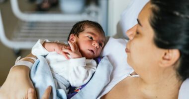 Woman lying down while holding her baby after labor.