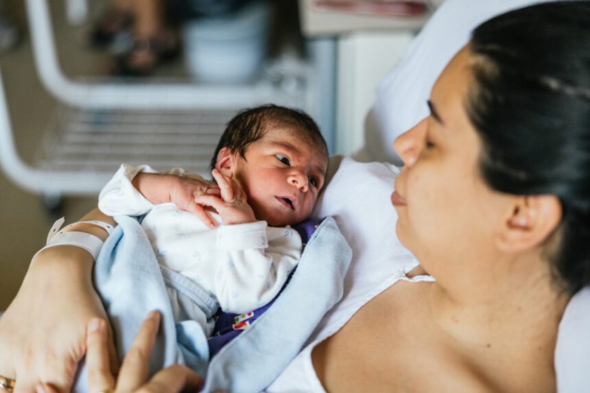 Woman lying down while holding her baby after labor.