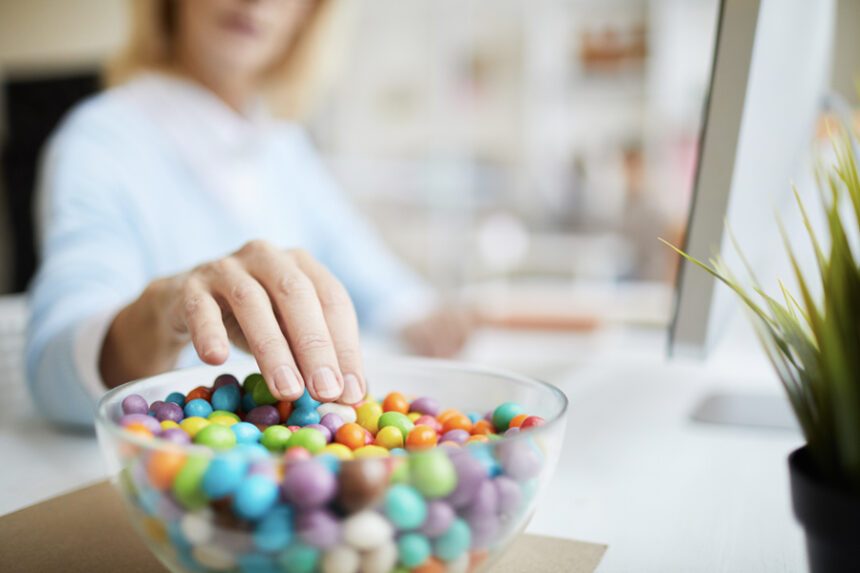Woman reaches for a bowl of colorful candies