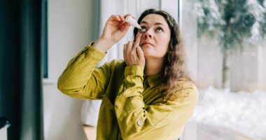 woman drops lubricating eye drops into her right eye
