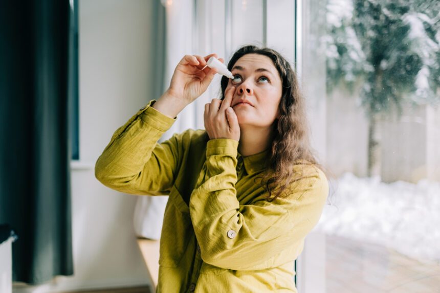 woman drops lubricating eye drops into her right eye